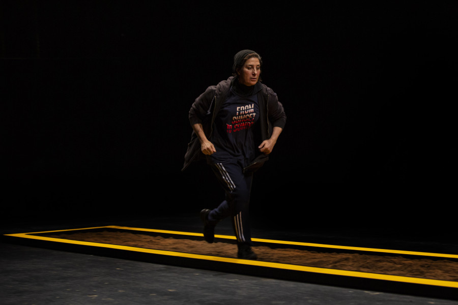 Eine Frau l&auml;uft im Hoodie in Eile &uuml;ber die B&uuml;hne, Theaterst&uuml;ck The child