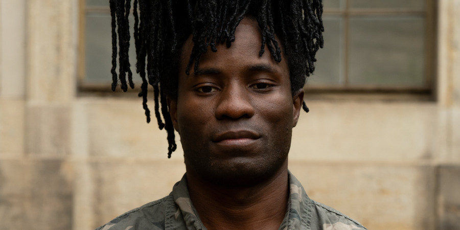 Das Bild zeigt ein Porträt des Choreografen Robert Ssempijja. Eine männlich gelesene Schwarze Person.